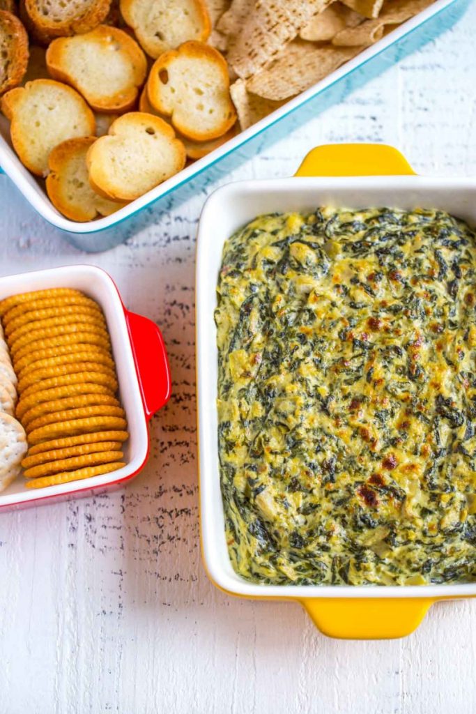 Best Spinach Artichoke Dip served with crackers and chips.
