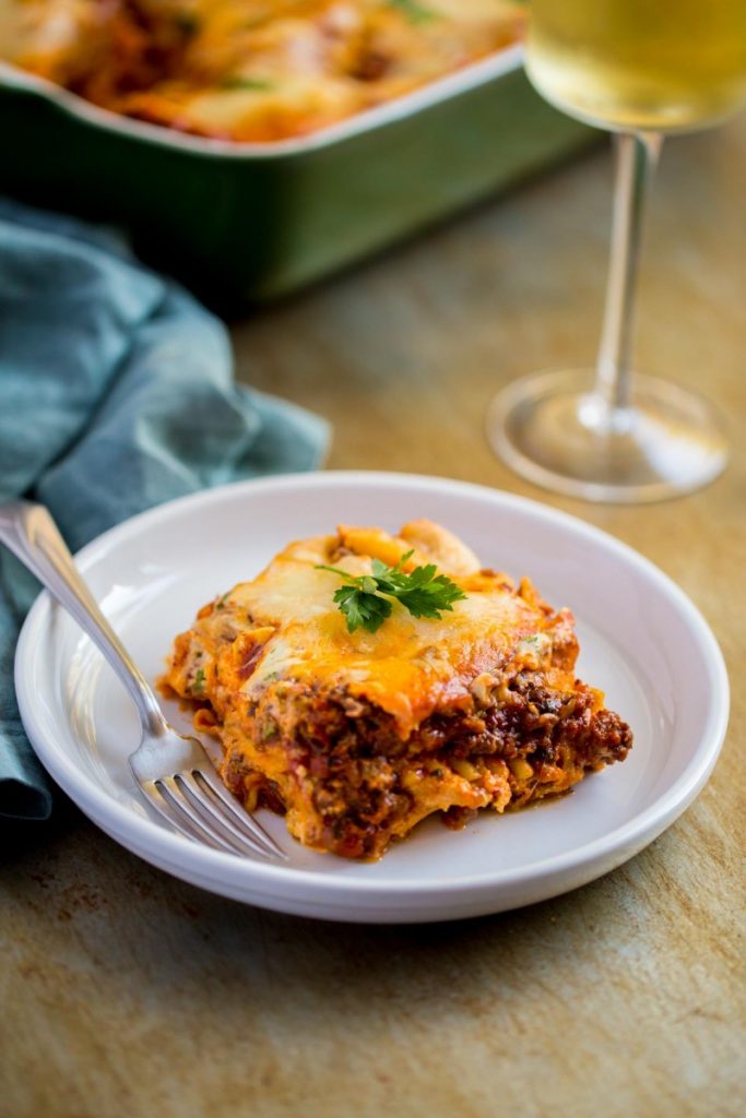 Meat lasagna with ricotta cheese filling, garnished with fresh parsley.