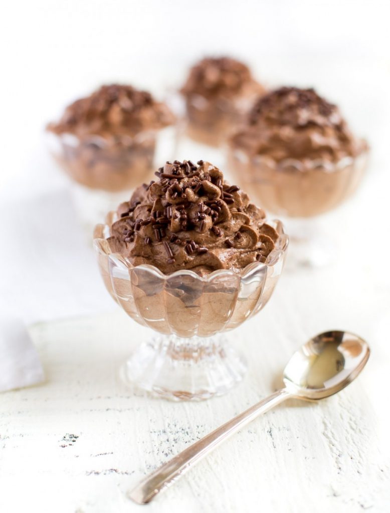 Four chocolate mousse cups on a white serving table.