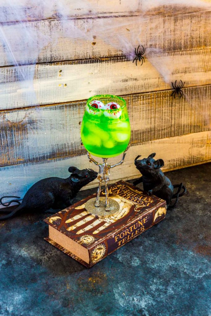 A Halloween tequila cocktail that glows green with Jello served in a scary skeleton glass.