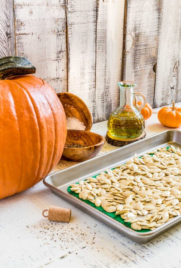 A batch of freshly-roasted pumpkin seeds with salt on a baking tray.