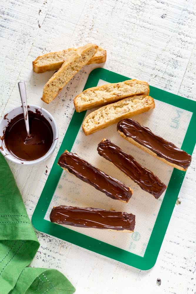 Chocolate-dipped biscotti cookies on a green-and-white silicone mat.