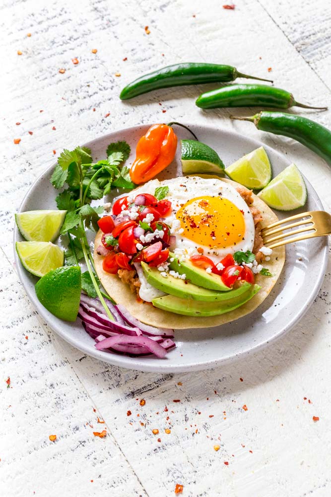 HUEVOS RANCHEROS served with fresh Mexican peppers and slices of lime.