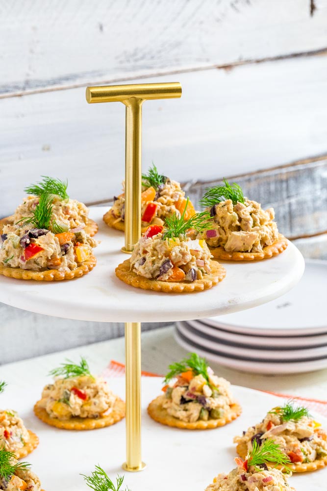 Tuna salad on individual crackers garnished with fresh dill served on a tiered tray.