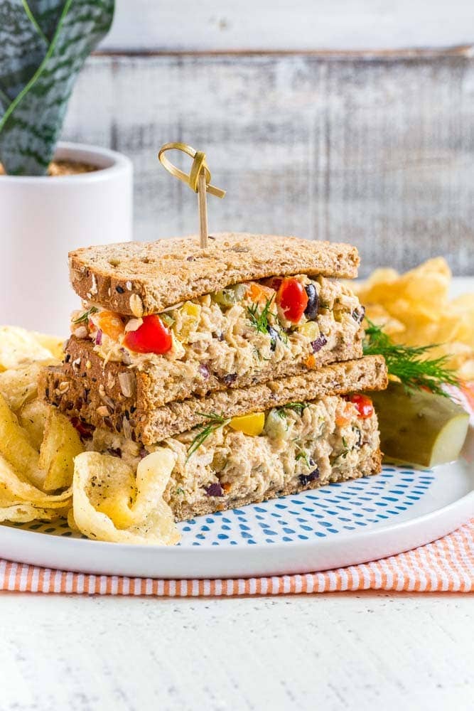 Tuna Salad Sandwich served on a round plate with chips and a pickle.