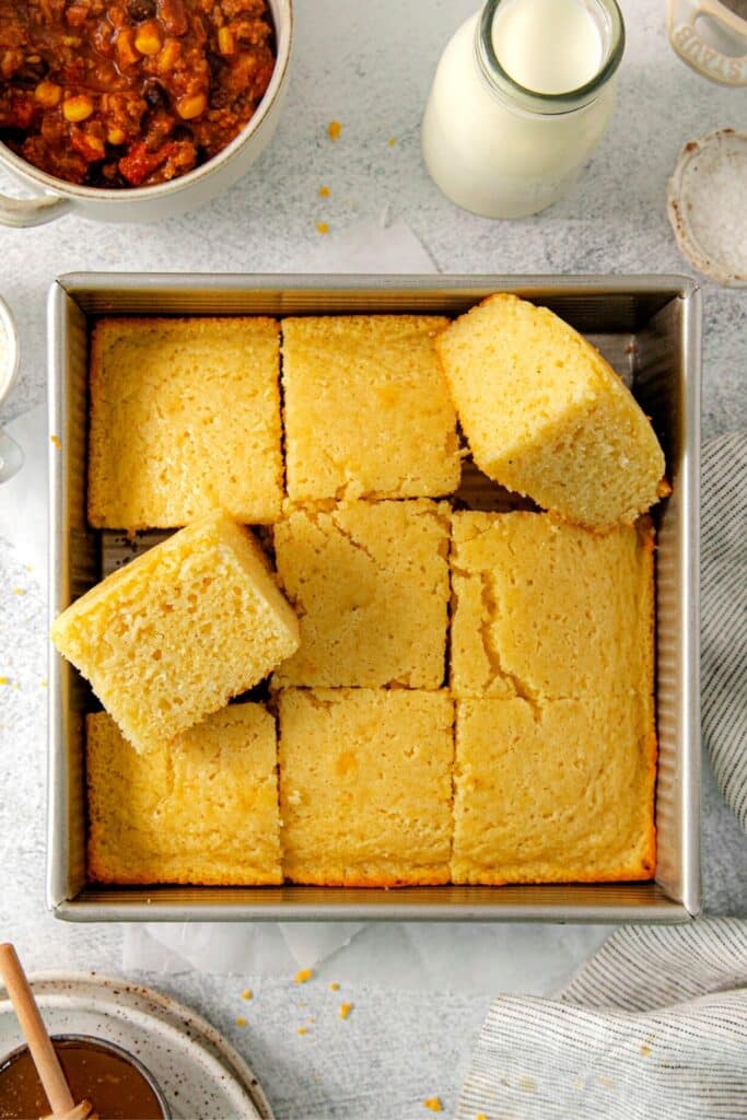 Delicious honey butter cornbread in a square metal pan, cut into 9 squares for serving.