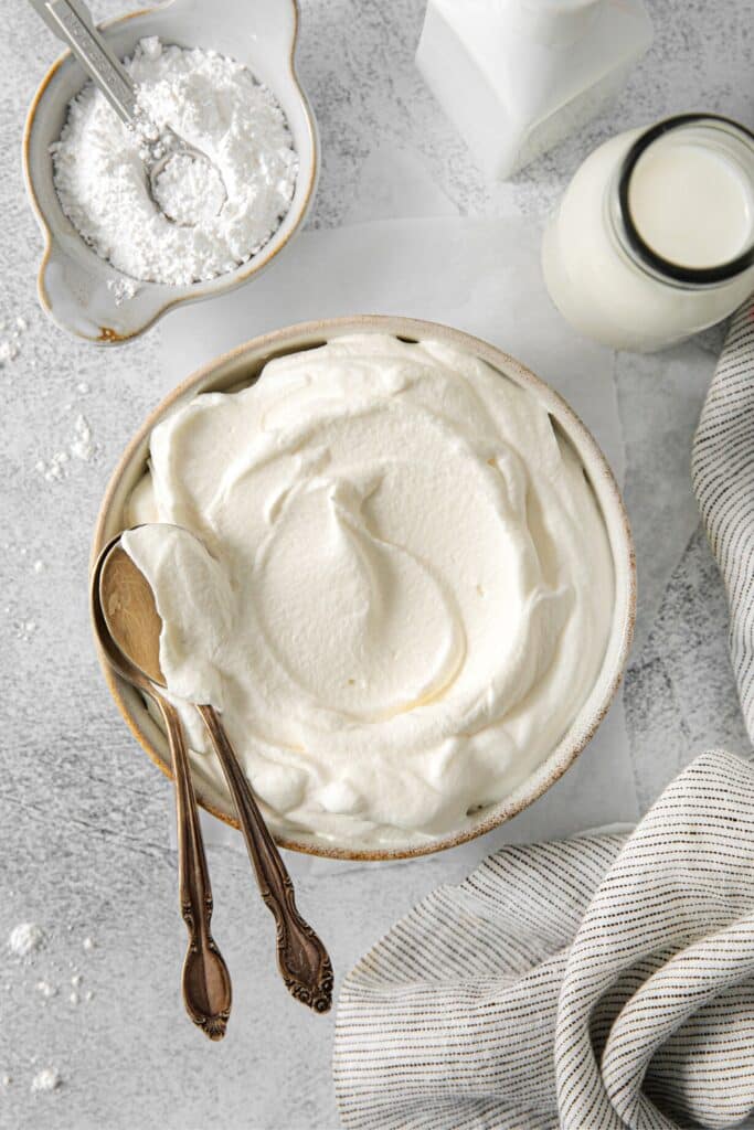 Freshly-made vanilla whipped cream in a serving bowl with 2 spoons.
