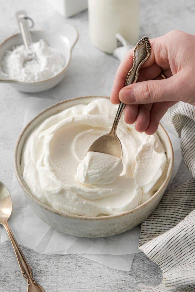Stabilized vanilla whipped cream in a bowl with a spoon.