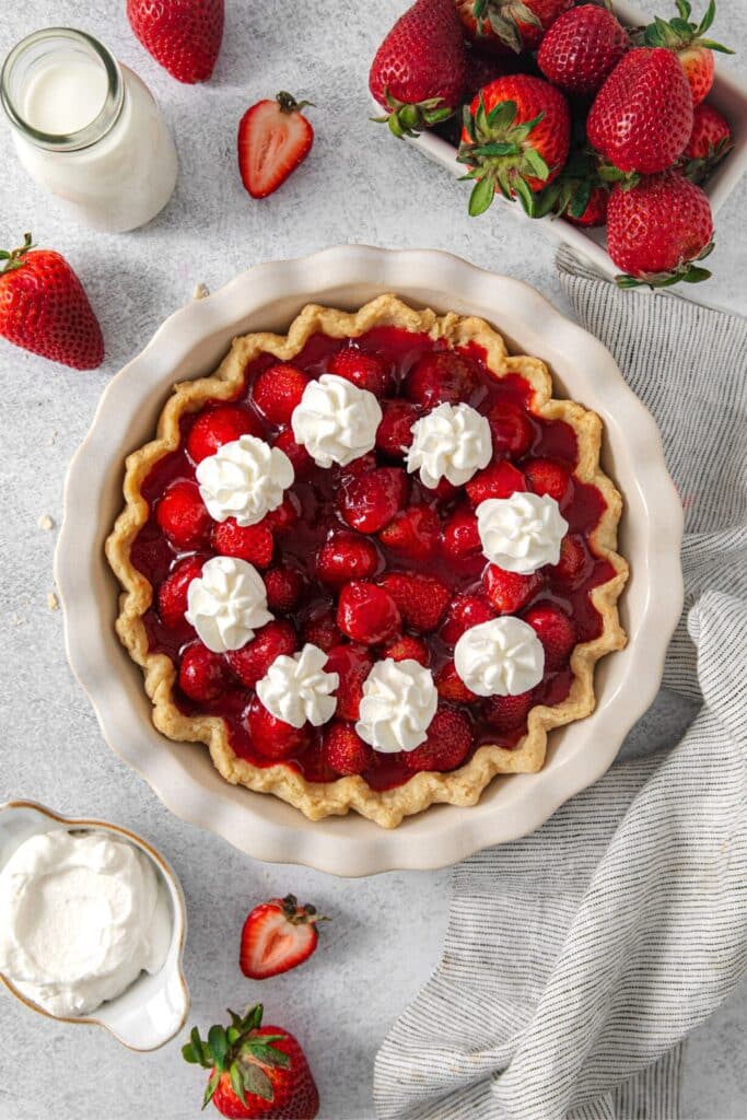 A no-bake fresh strawberry pie with dollops of fresh whipped cream.