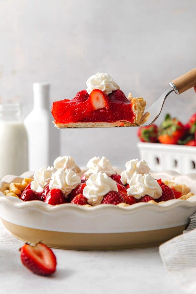 A slice of (no-bake) fresh strawberry pie being lifted up from the pie plate with a pie server.