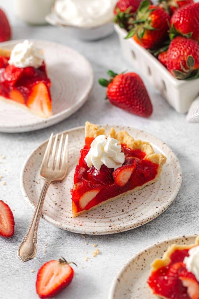 A beautiful slice of fresh strawberry pie on a dessert plate with fork.