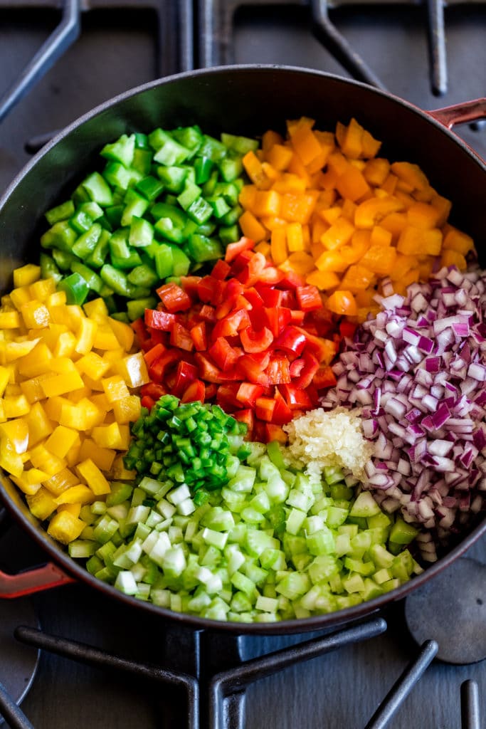 Colorful veggies being sauteed on the stovetop in a cast-iron pan.
