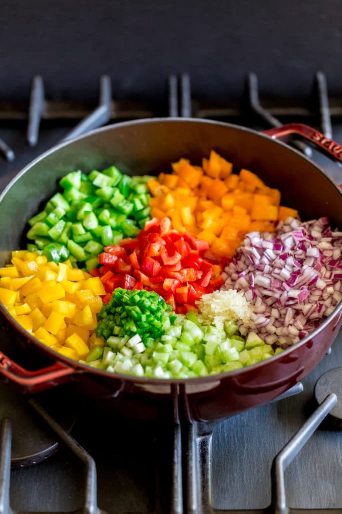 Bell peppers, onions, garlic and jalapenos being sauteed on the stovetop in a cast-iron pan.