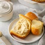 A bread plate with a serving of Parker House rolls with honey butter.