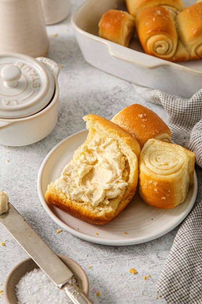 A bread plate with a serving of Parker House rolls with honey butter.