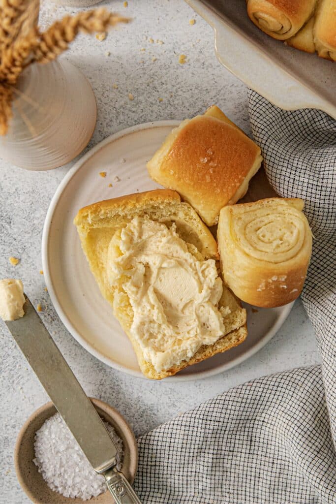 A Parker House Roll with honey butter spread.