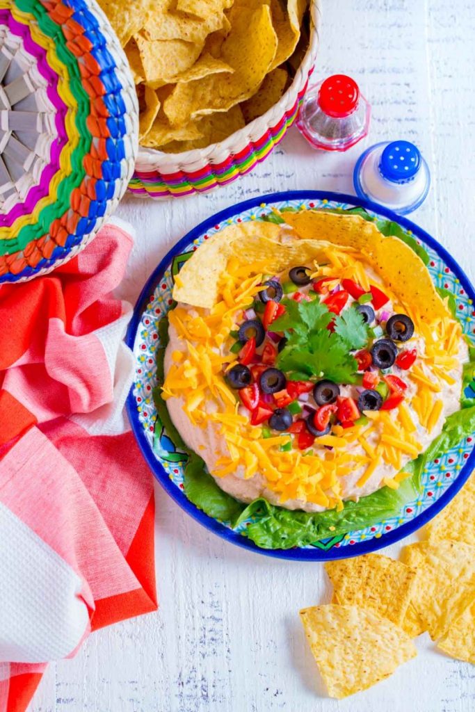 Fiesta taco dip served on an authentic Mexican plate alongside tortilla chips.