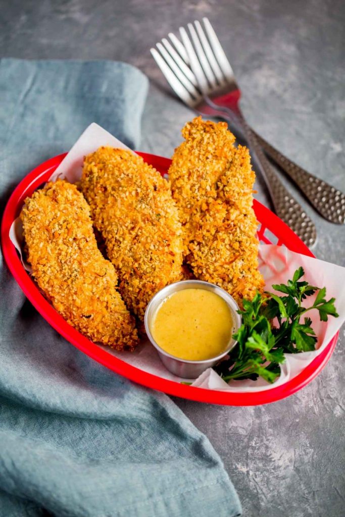 Chicken tenders served in a red food basket with homemade honey mustard sauce.