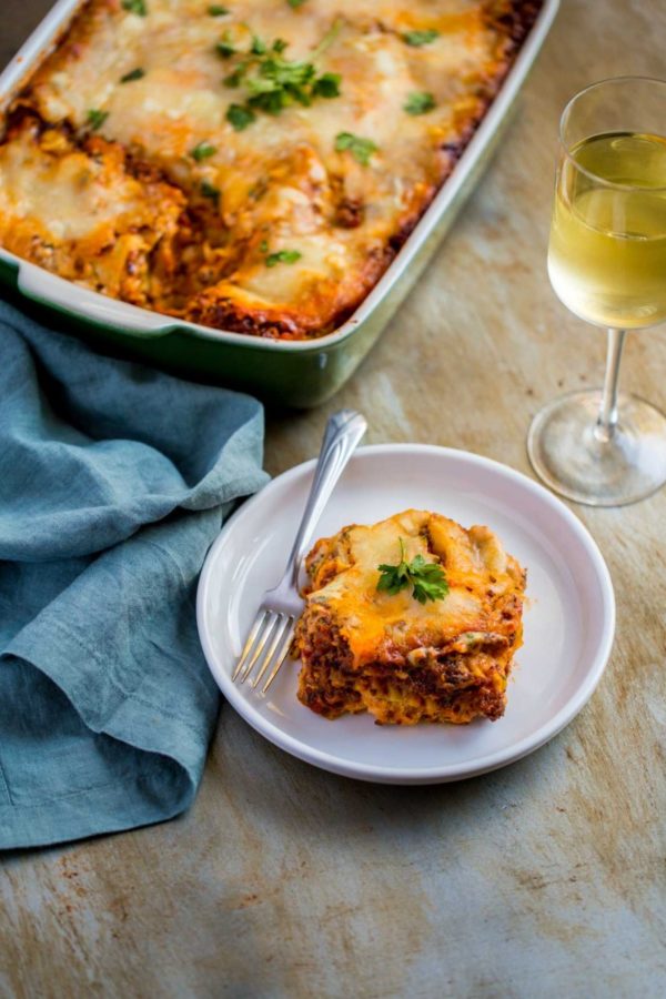 Legendary Homemade Meat Lasagna Recipe made with Ricotta cheese and served with a glass of wine.