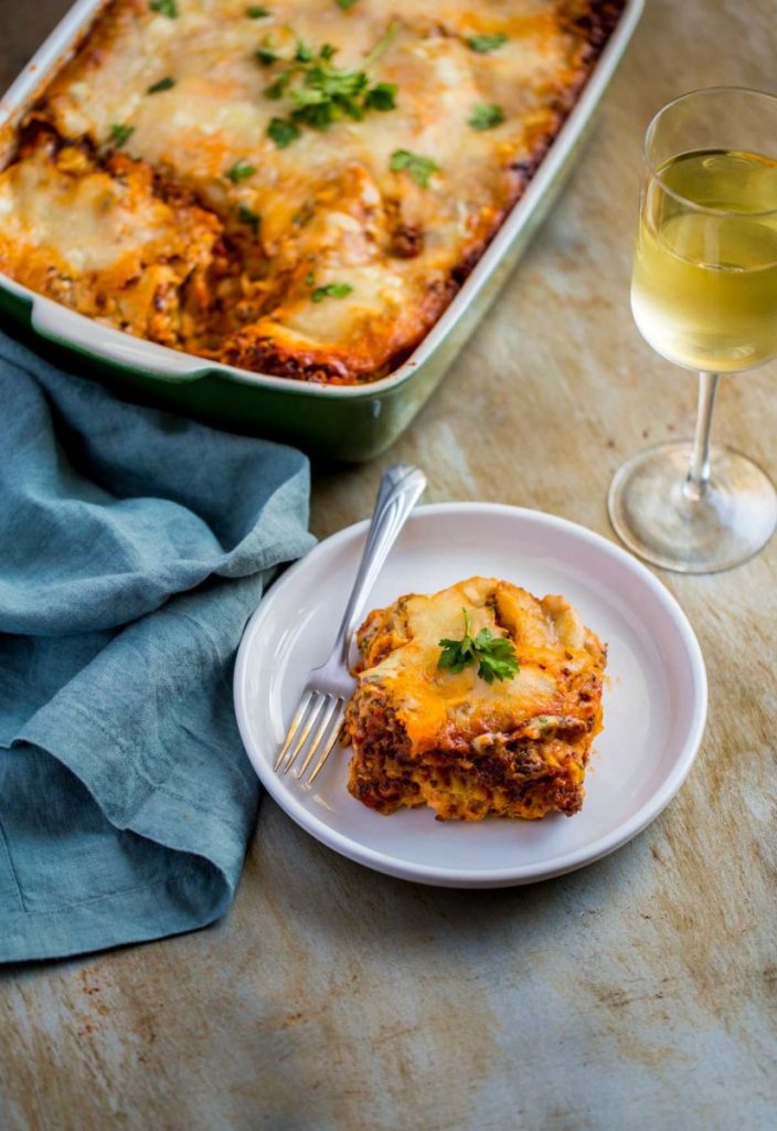 Easy lasagna with ricotta cheese served with a glass of wine.