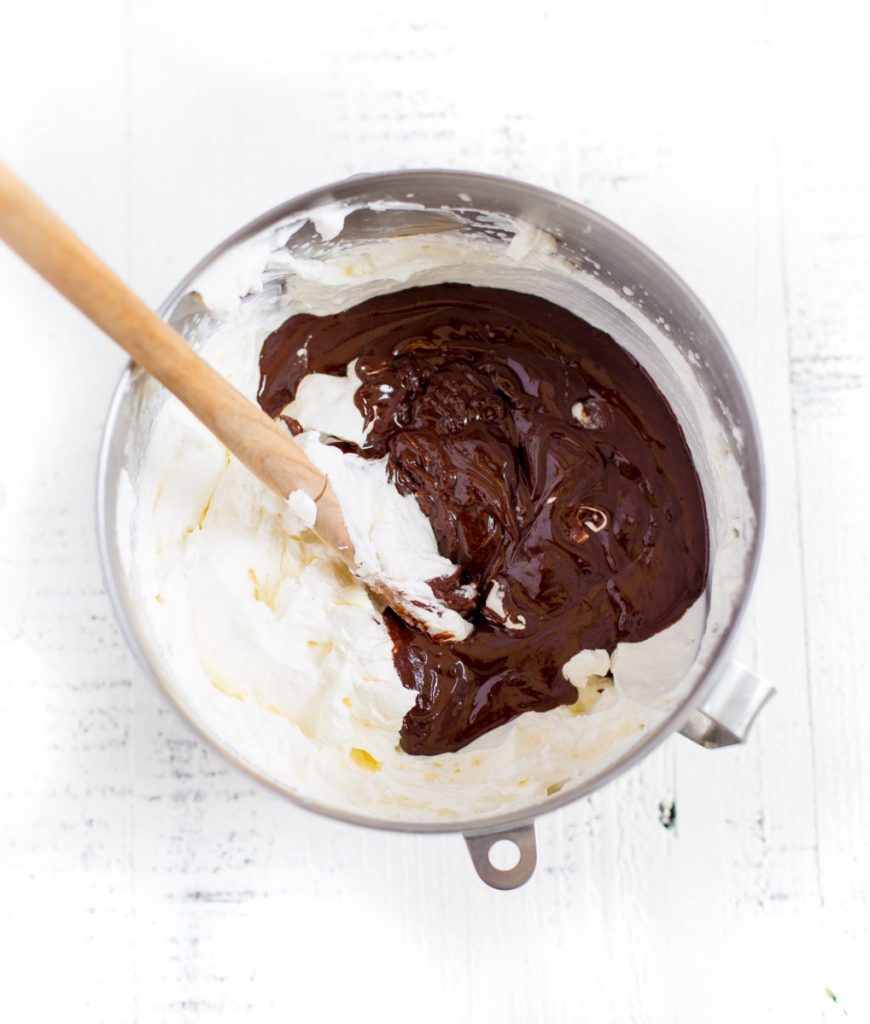 Whipped cream and chocolate ganache in a metal mixing bowl.