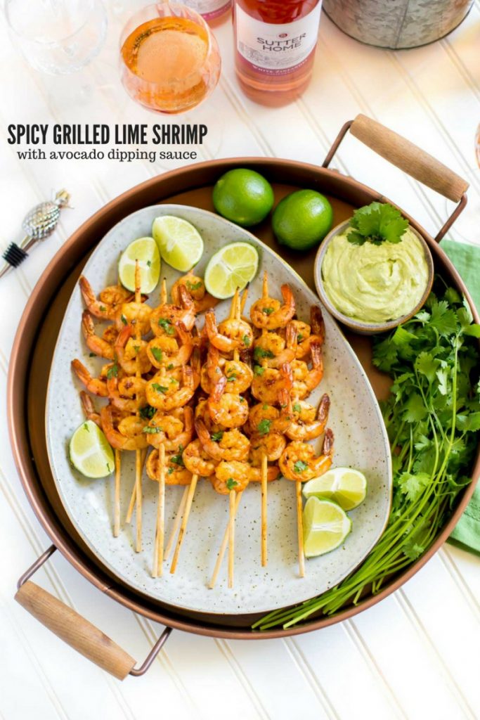 Grilled shrimp on an oval platter with lime slices.