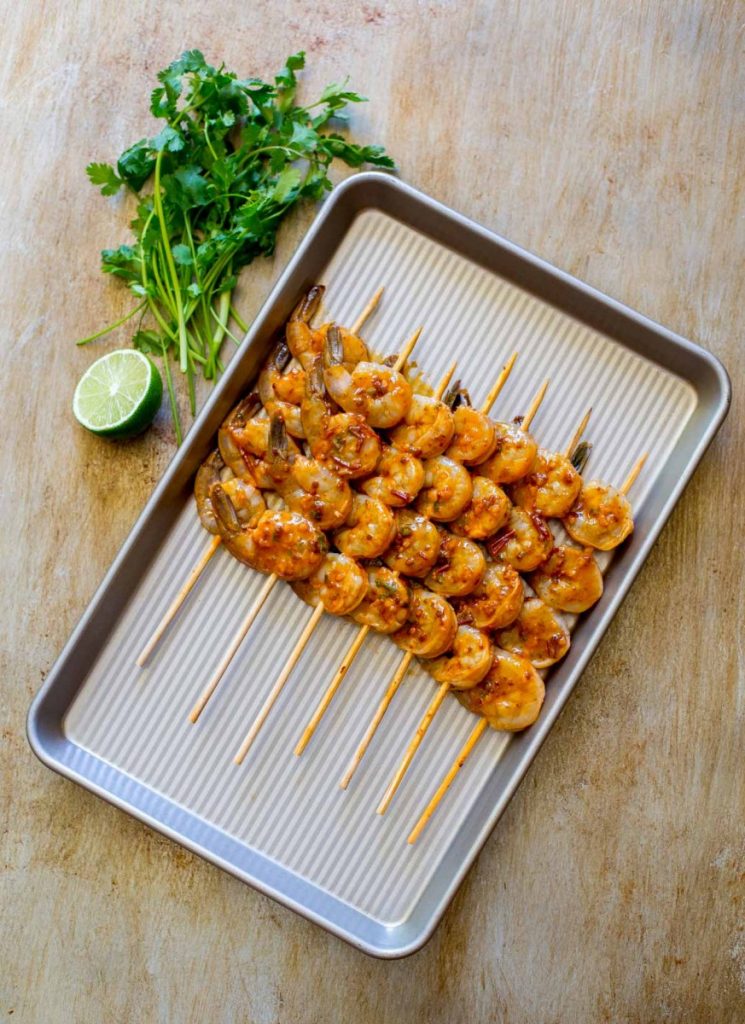 Grilled shrimp skewers lined up on a baking tray.
