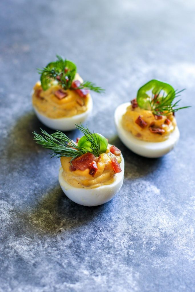 Deviled eggs garnished with dill and sliced jalapenos