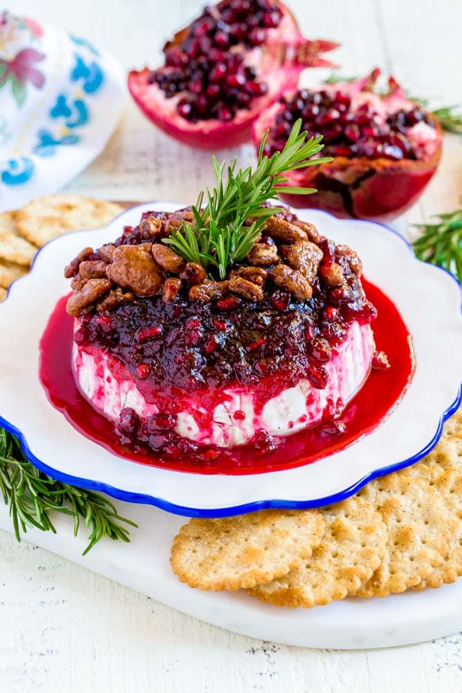 Baked brie with cranberry, garnished with rosemary and pecans.