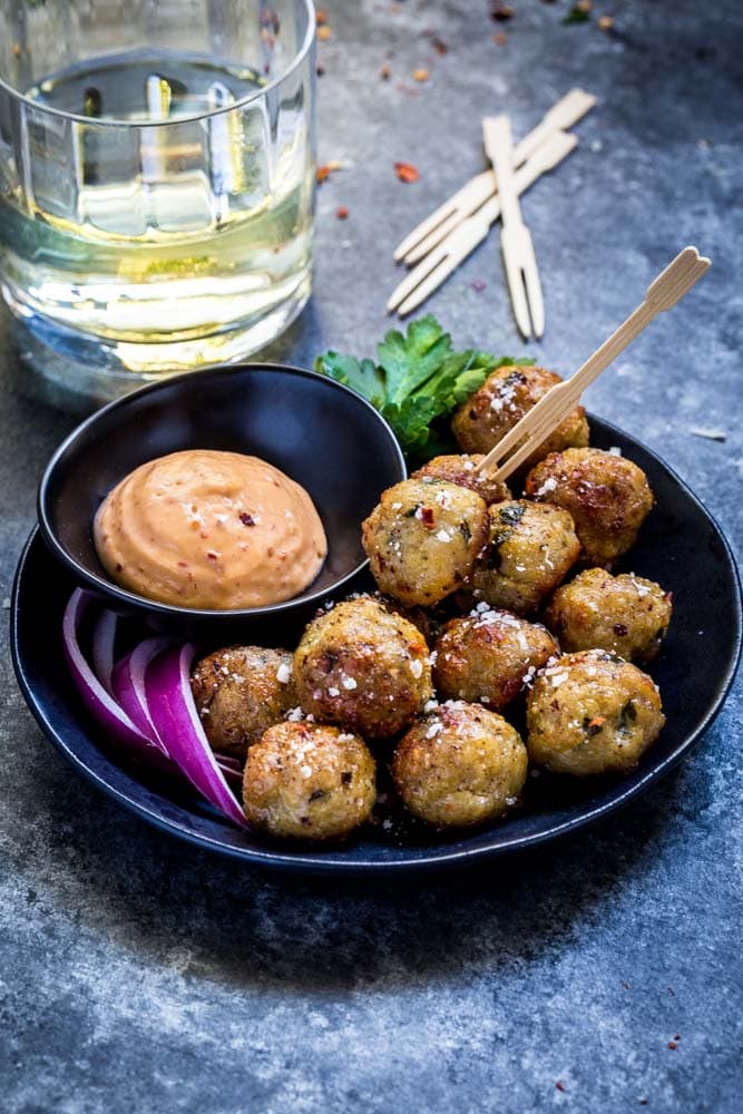 Oven baked meatballs on a plate with dipping sauce.