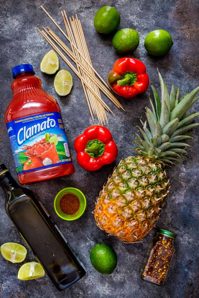 Flat lay image of a bottle of Clamato with ingredients for grilled shrimp kabobs.