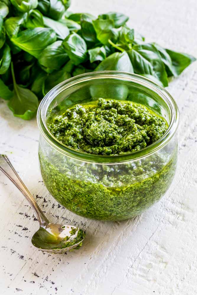 Fresh basil pesto in a Weck glass jar with a teaspoon beside it on the left.
