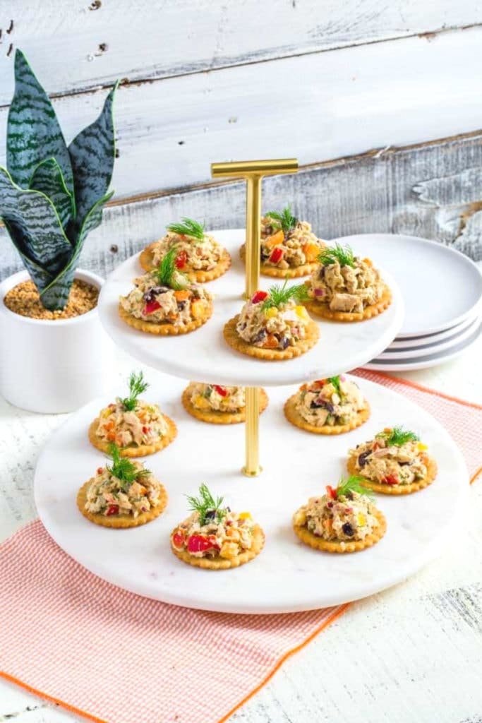 Tuna salad on round crackers served on a 2-tiered marble serving tray.