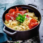 Lemon Pasta with Crispy Salami in a black Staub cocotte on a rustic table.