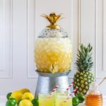 Pineapple Party Punch served in a glass pineapple container on a metal stand.