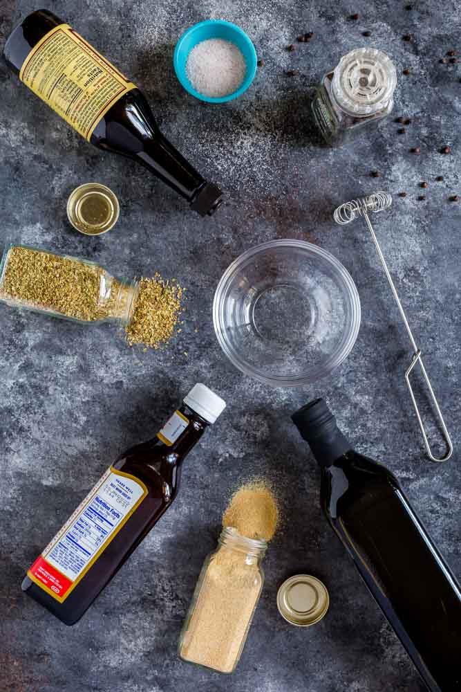 A flat-lay image of ingredients for steak marinade with a clear glass bowl and whisk.