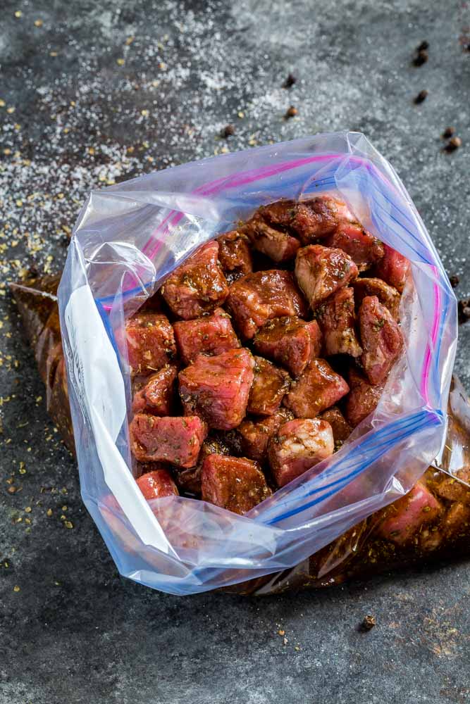 Zip-top kitchen bag with cubed beef covered in steak marinade.