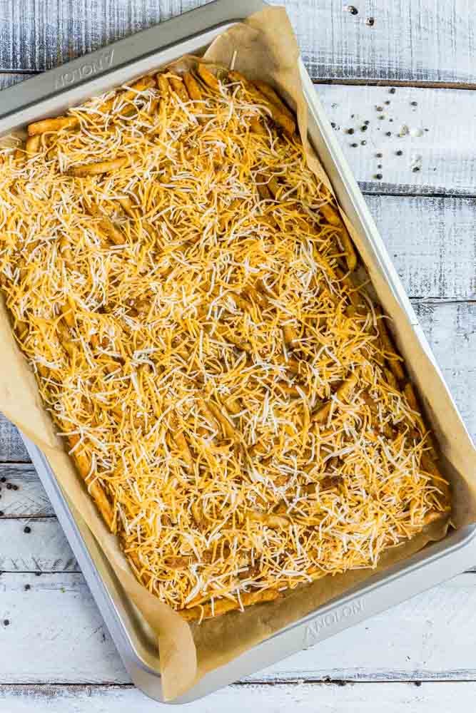 Crispy French fries with melted cheese on a baking sheet.
