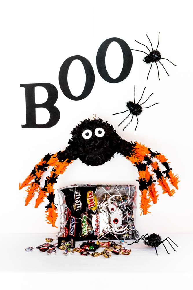 A paper-mache DIY spider hung over a bag of Halloween candy.