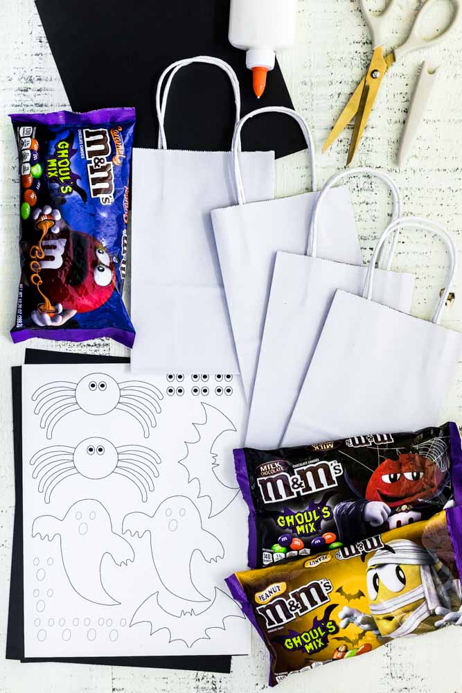 Supplies for making Halloween treat bags laid out on a white table.