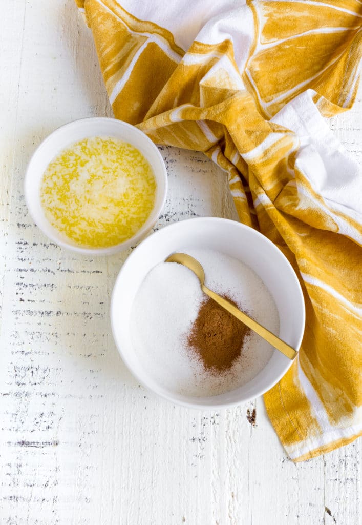 Ramekin of melted butter next to a small bowl filled with cinnamon and granulated sugar.