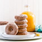 Apple cider donuts stacked vertically on a small white plate.