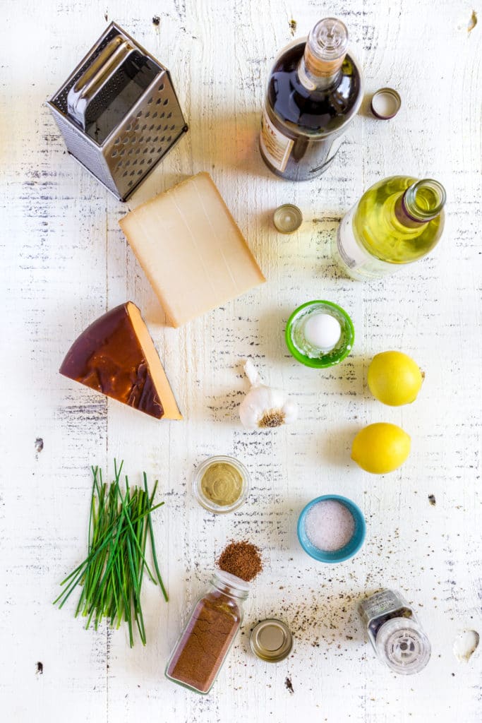Ingredients for making cheese fondue laid out on a white rustic table.