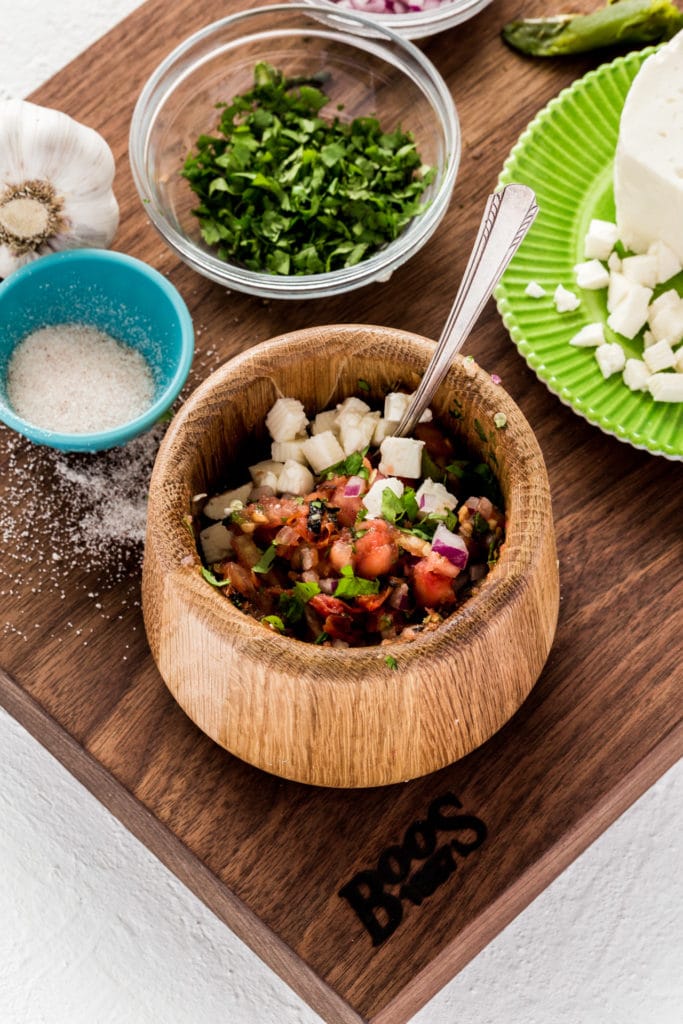 Garnishing Mexican salsa with diced cubes of panela cheese.