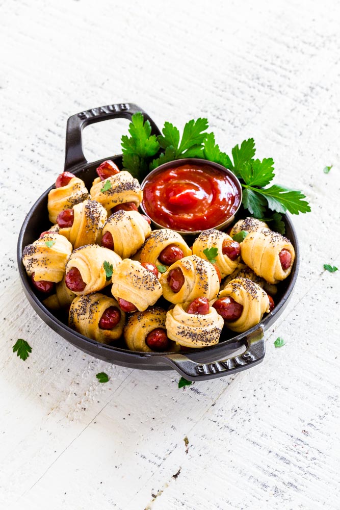 Mini Pigs in a Blanket garnished with chopped parsley, served with ketchup
