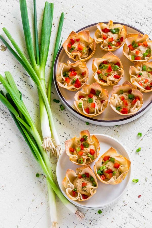 Crab rangoon wonton cups on a serving tray next to an individual serving.