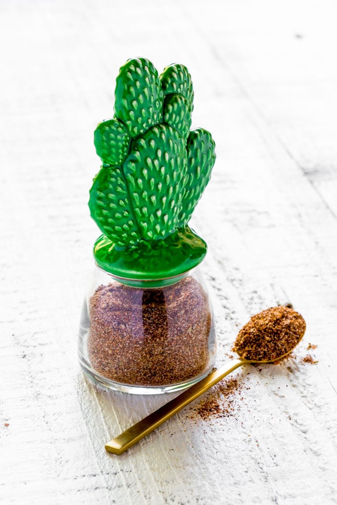 Homemade taco seasoning in a glass spice jar with a Mexican cactus lid.