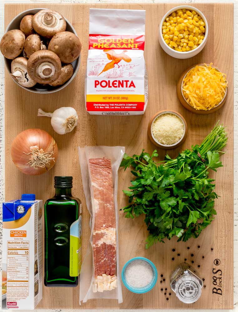 A flat-lay image of ingredients for Mushroom Polenta displayed on a maple board.