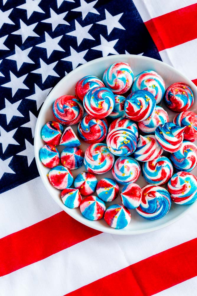 A small plate of red white and blue meringue cookies on a 4th of July tablecloth.