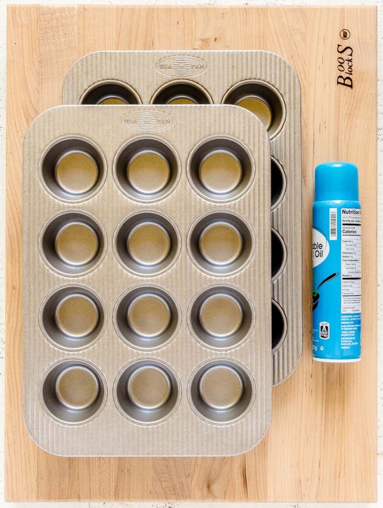 Two USA cupcake pans with 12 wells each, and a can of cooking spray.
